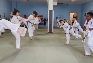 Adult and child karate students kicking